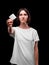 A serious young woman showing a packed condom on a black background. Healthy lifestyle concept. Copy space.