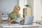 Serious young woman sitting at desk at home reading official notification letter