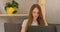 Serious young woman is working intently at laptop. Freelance girl working at home