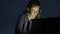 Serious young woman working on laptop in the dark room