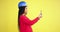 Seriously young woman engineer in a studio with a yellow background wall taking pictures using her phone of imagination