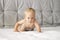 Seriuos baby boy crawling on the bed. Concentrated toddler on the white blanket
