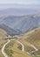 A serpentine mountain asphalt road meanders between hills and rocks