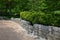 Serpentine rustic granite stone retaining wall in a public park, green trees and bushes, hexagonal paver blocks