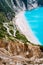 Serpentine zigzag road down to famous Myrtos Beach. Many tourists on the sunny beach, Kefalonia, Greece