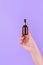 Serum bottle in female hands, top view. Transparent moisturizer for skin care. Nourishing essential oil in glass bottle with