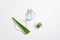 The serum bottle and fresh aloe vera are placed on the three podiums on a white background. Aloe vera contains organic acids and