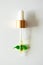 Serum in glass pipette on green plant leaf on white background, copy space. Skincare natural organic beauty product