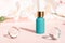 Serum pipette bottle with peptides, skin care cosmetic product mock up on floral pink backdrop. Cosmetics liquid mockup