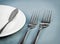 Served restaurant table with forks, white plate and knife