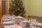 Served table with festive tableware near beautiful decorated Christmas tree in living room interior. Concept of new year holiday