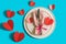 Served table with plate and cutlery forcelebration of Valentine\\\'s Day. On plate is napkin with paper heart. Flatlay on bright blu
