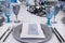 Served table in the restaurant - silver and blue wine glasses, plate, forks, knives and napkin with menu