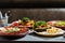 Served table with various dishes of the restaurant. Hot dog, barbecue pork ribs, steak, Carbonara paste and crab salad. Top view.