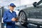 Serviceman with digital tablet on the background of the car in the car service