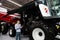 Serviceman with digital tablet on a next to ombine harvester with open hood..