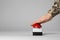 Serviceman pressing red button of nuclear weapon on light gray background, closeup with space for text. War concept