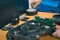 Serviceman stripping and removing electric components on robotic lawnmower, motorized lawnmower being serviced on a table after a