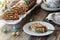 A serving of carrot cake jelly roll with a platter of the same in behind.