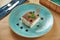 A serving of classic Italian dessert - tiramisu on a blue plate on a wooden background. Restaurant table setting. Tasty pastry