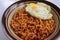 serving fried noodles in a bowl with an egg - medium close up