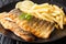 Serving of grilled sea bass fillet with a side dish of french fries close-up on a plate. horizontal