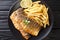 Serving of grilled sea bass fillet with a side dish of french fries close-up on a plate. Horizontal top view