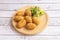 Serving of ham croquettes on a round wooden plate