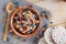 Serving muesli scattering of wild berries, nuts on wooden table