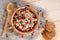 Serving muesli scattering of wild berries, nuts on wooden table