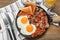 Serving pan with fried eggs, mushrooms, beans, bacon, tomatoes and toasted bread on wooden table, flat lay. Traditional English