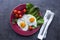 Serving plate with fried eggs, salad and tomatoes at black background