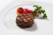 Serving a steak on a white plate with tomato, vegetables garnish. Elegant plating of steak with grill marks