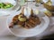 Serving of steaks with fried onions, potato with sauce filling, and salads