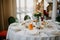 Serving the wedding table. Restaurant business. Glasses, white plates and cutlery on a round table decorated with roses in a white