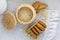 Sesame cookies on a white plate, sesame seeds in a wicker basket, rough woven tablecloth