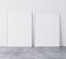 Set of 2 white vertical modern frames A3, A4, frame mock up on white wall standing on gray floor.