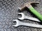 Set of 2 wrenches and a nail hammer placed on a dark steel background - top view