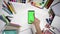 Set of 26 gestures on green screen of the smartphone lying on white table among school accessories