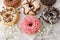 Set of assorted colorful white and dark chocolate glazed donuts with mixed sprinkles on paper closeup on stone table