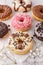 Set of assorted colorful white and dark chocolate glazed donuts with mixed sprinkles on paper closeup on stone table