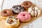 Set of assorted colorful white and dark chocolate glazed donuts with mixed sprinkles on paper on wooden table