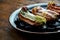 Set of assorted French custard eclairs with custard and assorted toppings served on a black plate on a wooden background.