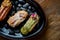 Set of assorted French custard eclairs with custard and assorted toppings served on a black plate on a wooden background.