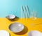 Set of assorted plates, straws and a glass on yellow and blue background