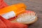Set of bathing accessories - orange towel, hairbrush and cosmetics for pampering on wooden background