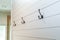 A set of black rustic farmhouse or industrial style hanging hooks on white shiplap planks in a bathroom, bedroom or