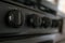 A set of black stove knobs with white writing waits in a camper at day time.