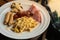 set of breakfast that compose of scrambled eggs with cheese and ham, sausage, bacon, ham, and grilled mushroom placed on a white