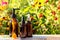 Set of brown glass bottles with serum, essential oil or other cosmetic product on bright floral background. Natural